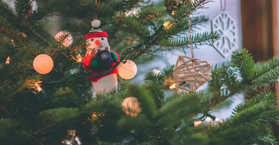 Close-up of a decorated Christmas tree featuring a snowman ornament and glowing lights.