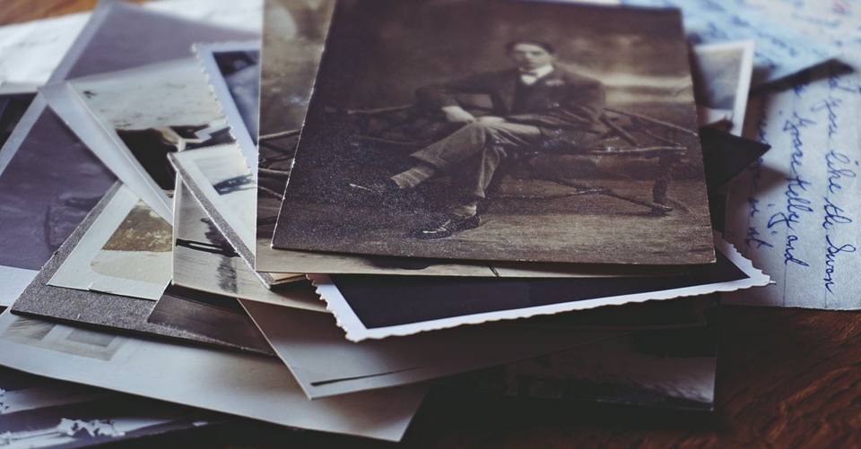 Vintage family photographs and handwritten letters are spread across a wooden table.