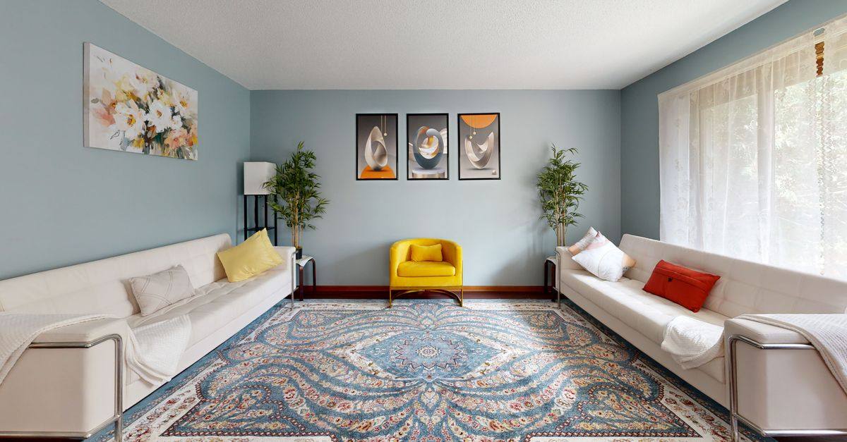 A bright living room with framed abstract art, colorful seating, and plants.