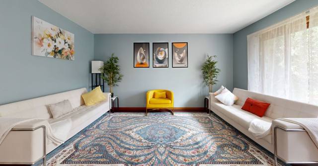 A bright living room with framed abstract art, colorful seating, and plants.