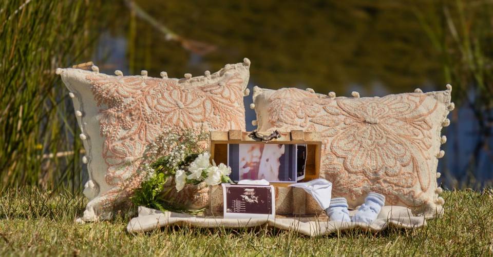 Baby socks, ultrasound photographs, flowers, and framed photos form an outdoor announcement display.
