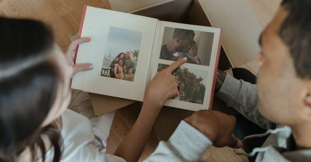 A couple looks through a photo album together in their home.