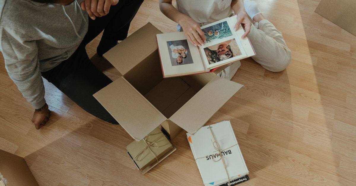 A couple looks through a photo album while unpacking in a new home.