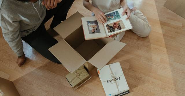 A couple looks through a photo album while unpacking in a new home.