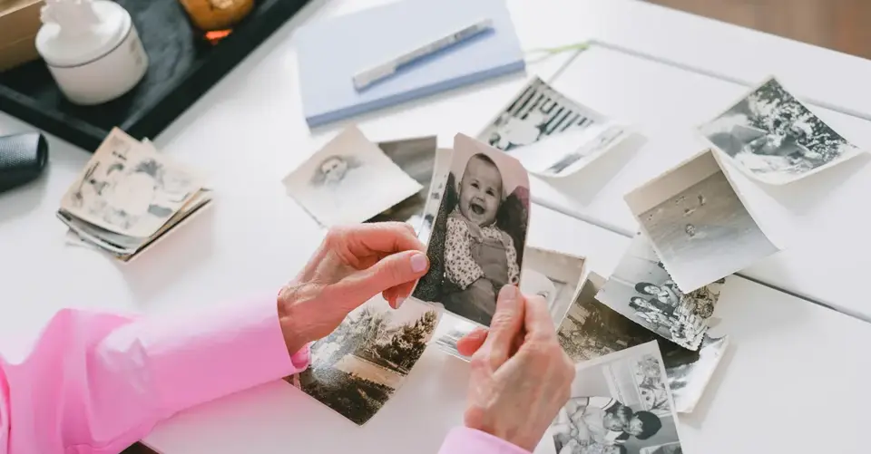 A person sorts black-and-white family photographs across a white table.