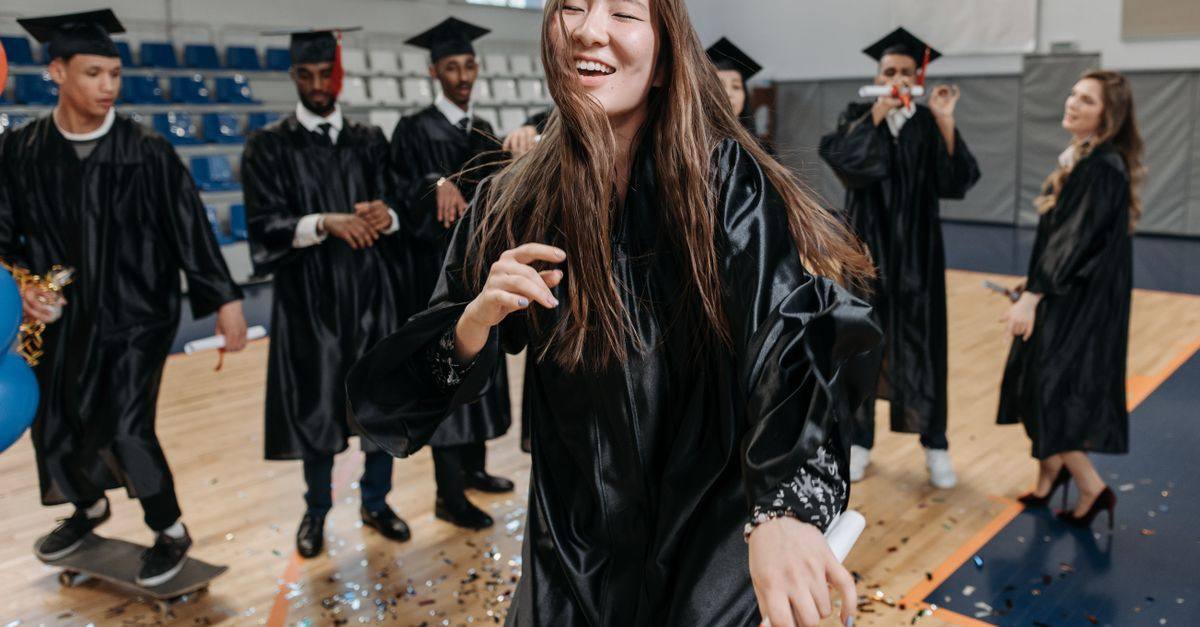 Graduates in caps and gowns celebrate together with confetti.