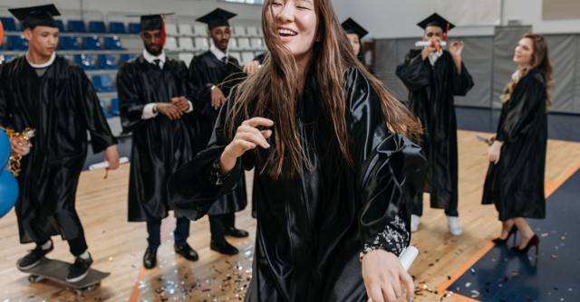 Graduates in caps and gowns celebrate together with confetti.