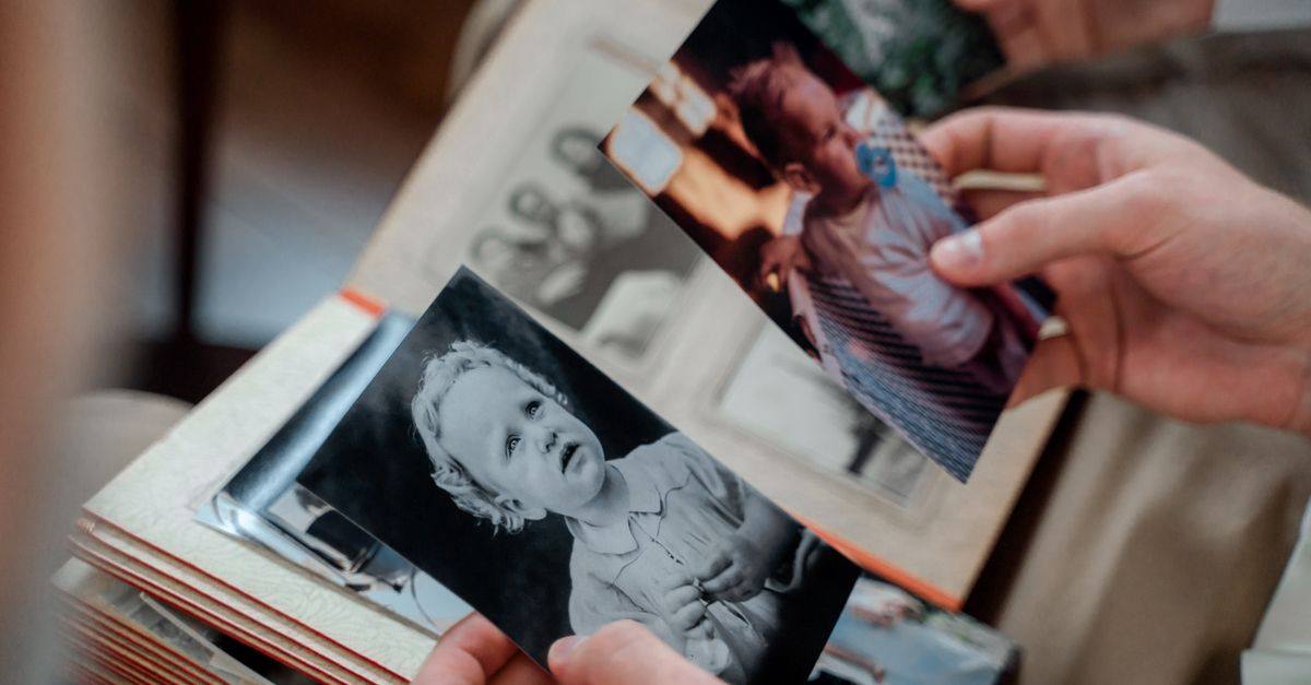 Hands turn through an album of old family photographs.